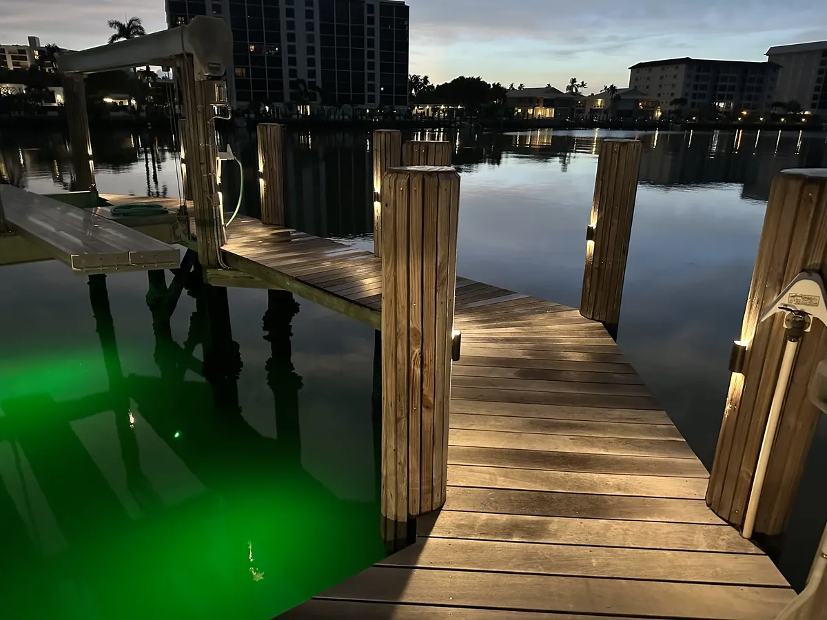 Private Naples dock at night with underwater lighting glowing beneath the walkway