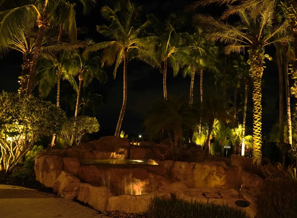 Paseo community amenity area in Fort Myers with palms and tiki structures lit at night
