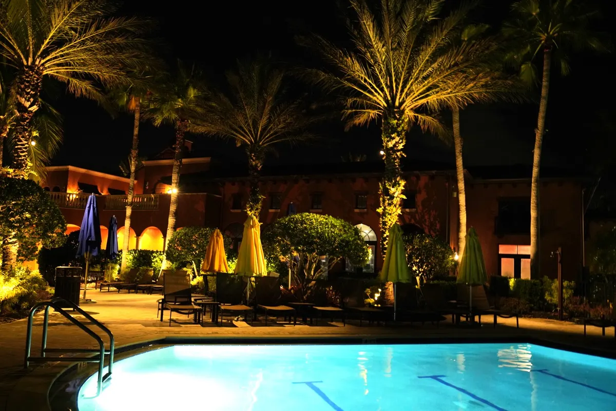 Paseo community amenity core at night — palms and structures lit by Spectrum Nightscapes