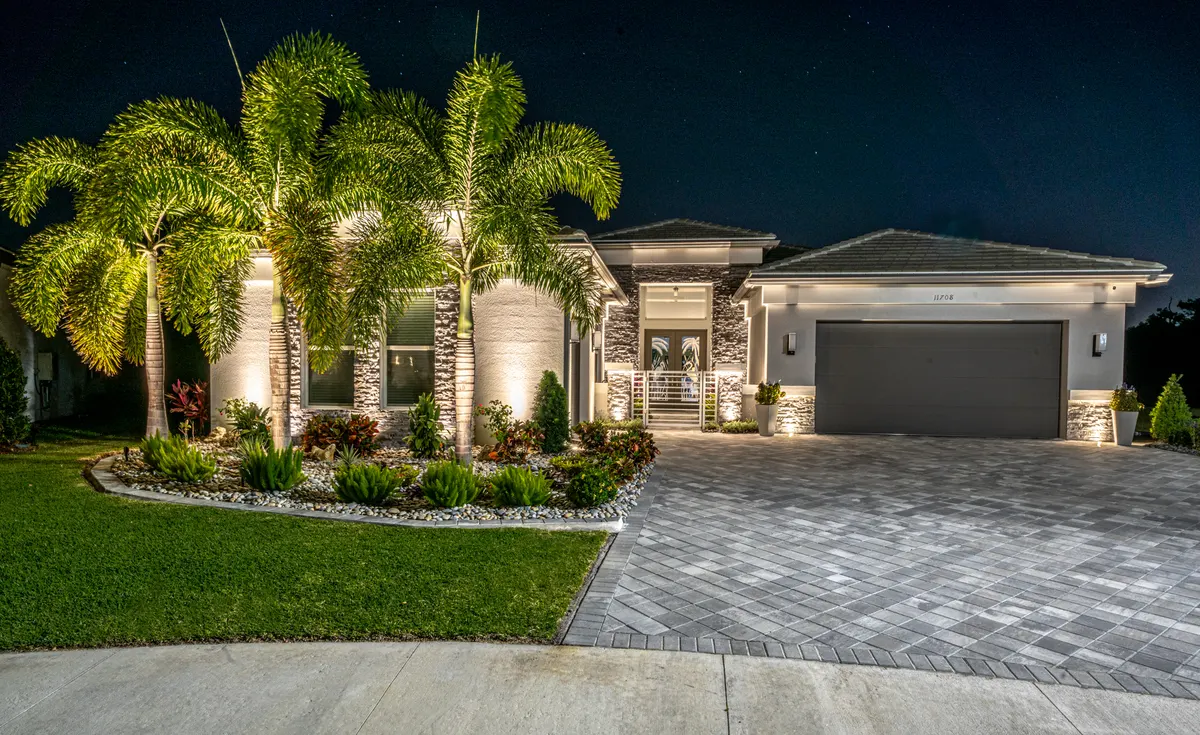Valencia Trails home at night with grazed stone facade and uplit palms